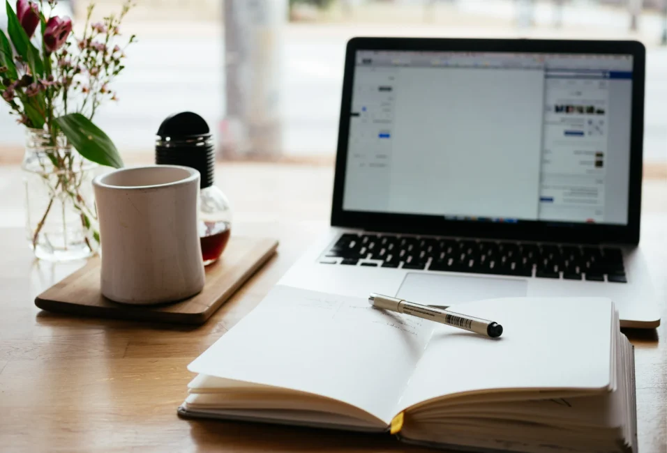 16 A desk with a laptop, mug, notebook and pen