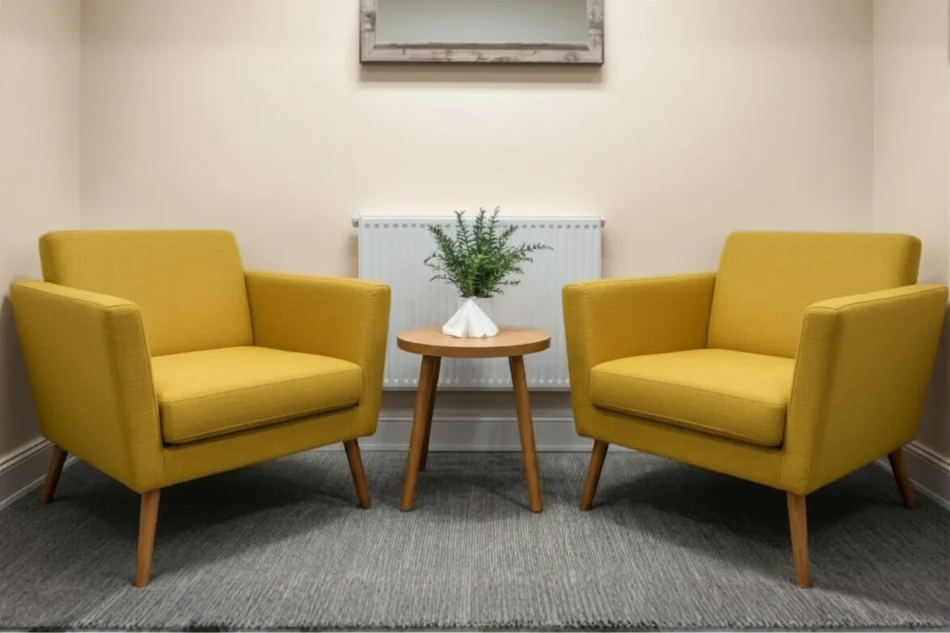 room Counselling room with two yellow chairs and a table with a plant